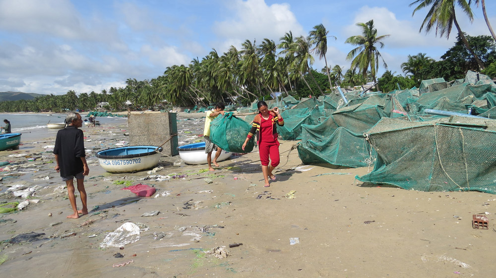 Người dân khiêng tấm lưới rách chất lên bờ.