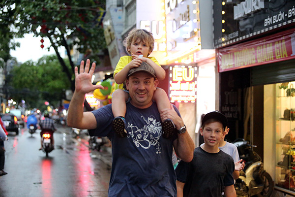 Một gia đình khách du lịch nước ngoài vui vẻ đi dạo dưới trời mưa