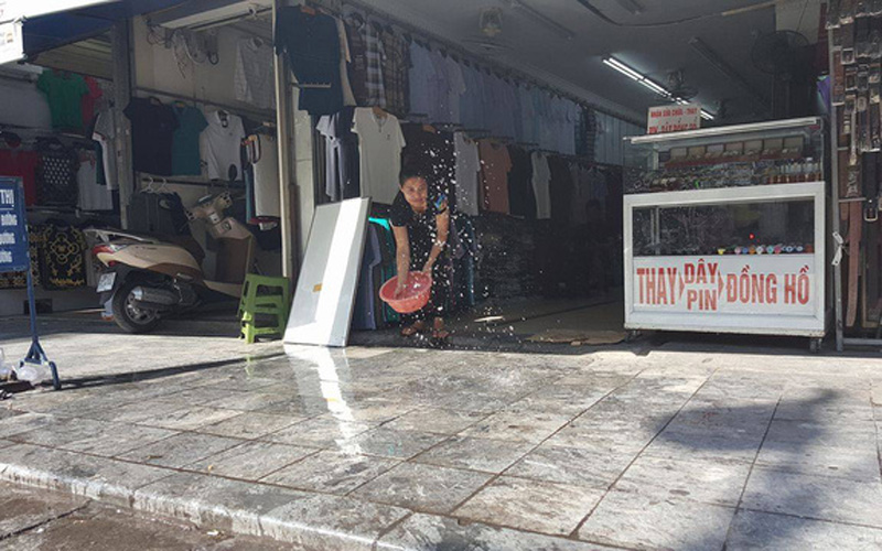 Trên phố Hàng Ngang, các chủ cửa hàng phải liên tục tạt nước để giảm nhiệt