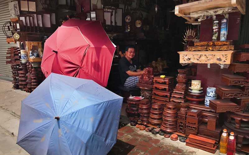 Chủ cửa hàng ngay sát lề đường Lê Duẩn dùng ô che nắng để đỡ hắt nóng vào hiên nhà.