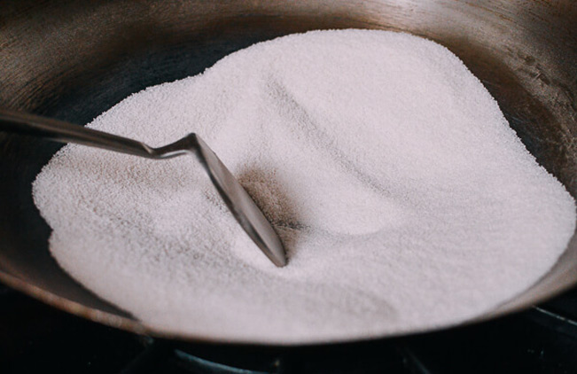 Cho muối hạt vào chảo rang khô khoảng 15 phút tới khi muối chuyển màu nâu nhạt.