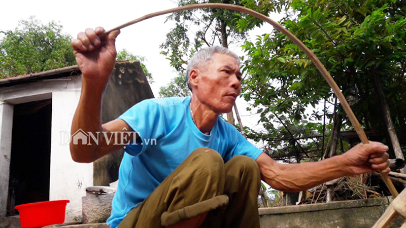 Ông Lê Đình Định đang thử độ dẻo dai của thanh tre trên chiếc bẫy kẹp chuột. Ảnh: Lê Tập