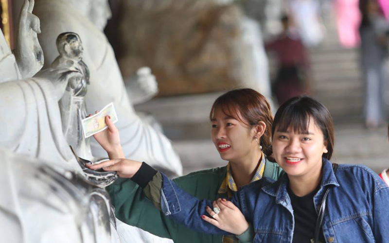 Xoa tiền vào các bức tượng La Hán với mong muốn cầu may của hai cô gái trẻ