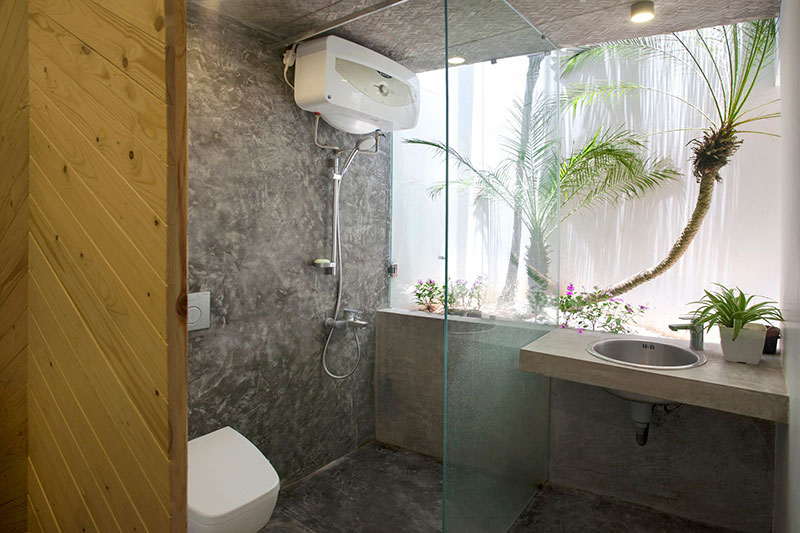 Phòng tắm với cửa kính lớn nhìn ra được cây xanh phía ngoài, tạo nên không gian thoáng mát. Có thể thấy rõ sự linh hoạt trong việc sử dụng vật liệu và thiết bị của kiến trúc sư. Tuy diện tích có hạn nhưng vẫn đầy đủ và hiện đại.