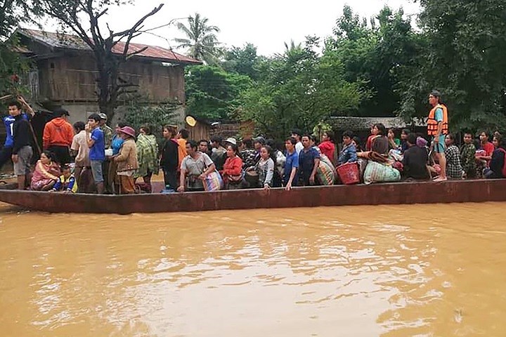 Một nhóm dân làng sơ tán bằng thuyền. Công ty SK Engineering & Construction (của Hàn Quốc) đã huy động trực thăng và thuyền để hỗ trợ công tác cứu hộ. Ảnh: EPA.