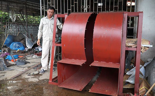 Ông Nguyễn Văn Chế và chiếc máy sấy hàng nông sản đang lắp đặt dở dang.