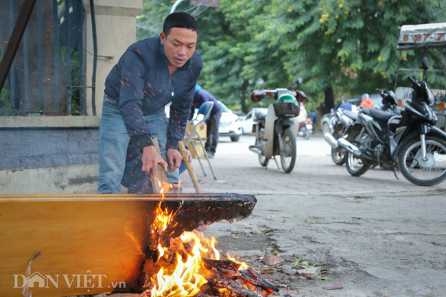 Người đàn ông dùng nguyên một tấm gỗ lớn để nhóm lửa.