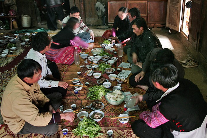 Sau khi hoàn tất các thủ tục thờ cúng tổ tiên, cả gia đình quây quần cùng nhau ăn thịt lợn, uống rượu ngô và mời tổ tiên về ăn cùng bữa cơm ngày Tết.