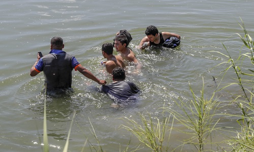 Một nhóm người di cư đang vượt qua sông Rio Grande ở biên giới Mỹ - Mexico tháng 12/2018. Ảnh: AP.