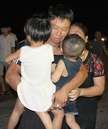 Thuyền viên Định Trọng Hậu ôm chầm lấy 2 con ngay khi vừa lên bờ, nước mắt rơm rớm. Ảnh: Nguyễn Hải.