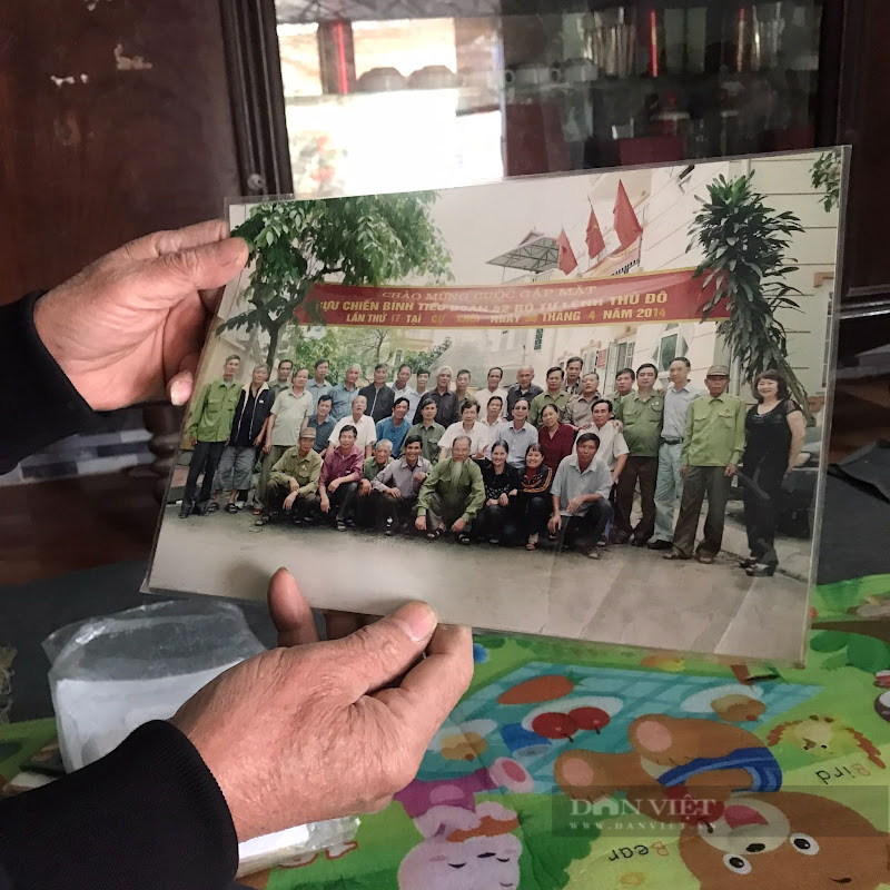 Người lính già cầm trên tay bức ảnh kỷ niệm cùng đồng đội 
