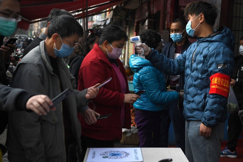 Mọi người quét mã QR trên điện thoại của họ trong khi các tình nguyện viên kiểm tra nhiệt độ của họ trước khi bước vào một khu chợ ở Côn Minh, thuộc tỉnh Vân Nam, miền nam Trung Quốc. Ảnh: @SCMP.