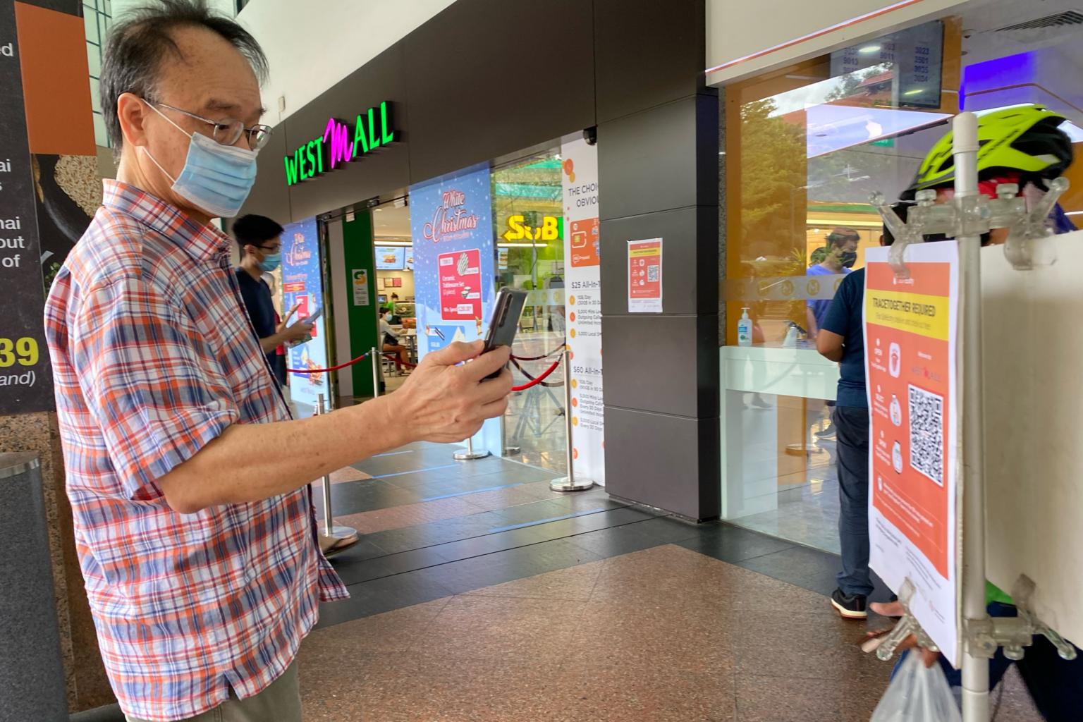 Người dân Singapore dùng ứng dụng TraceToghether quét mã QR tại các cửa trung tâm thương mại. Ảnh: @AFP.