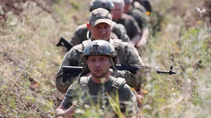 Tổng thống Ukraine Volodymyr Zelenskiy và các quân nhân đi bộ trong chiến hào gần chiến tuyến với lực lượng ly khai do Nga hậu thuẫn ở Krasnohorivka thuộc Vùng Donetsk, Ukraine, ngày 7 tháng 8 năm 2020. Ảnh: @REUTERS/Gleb Garanich.