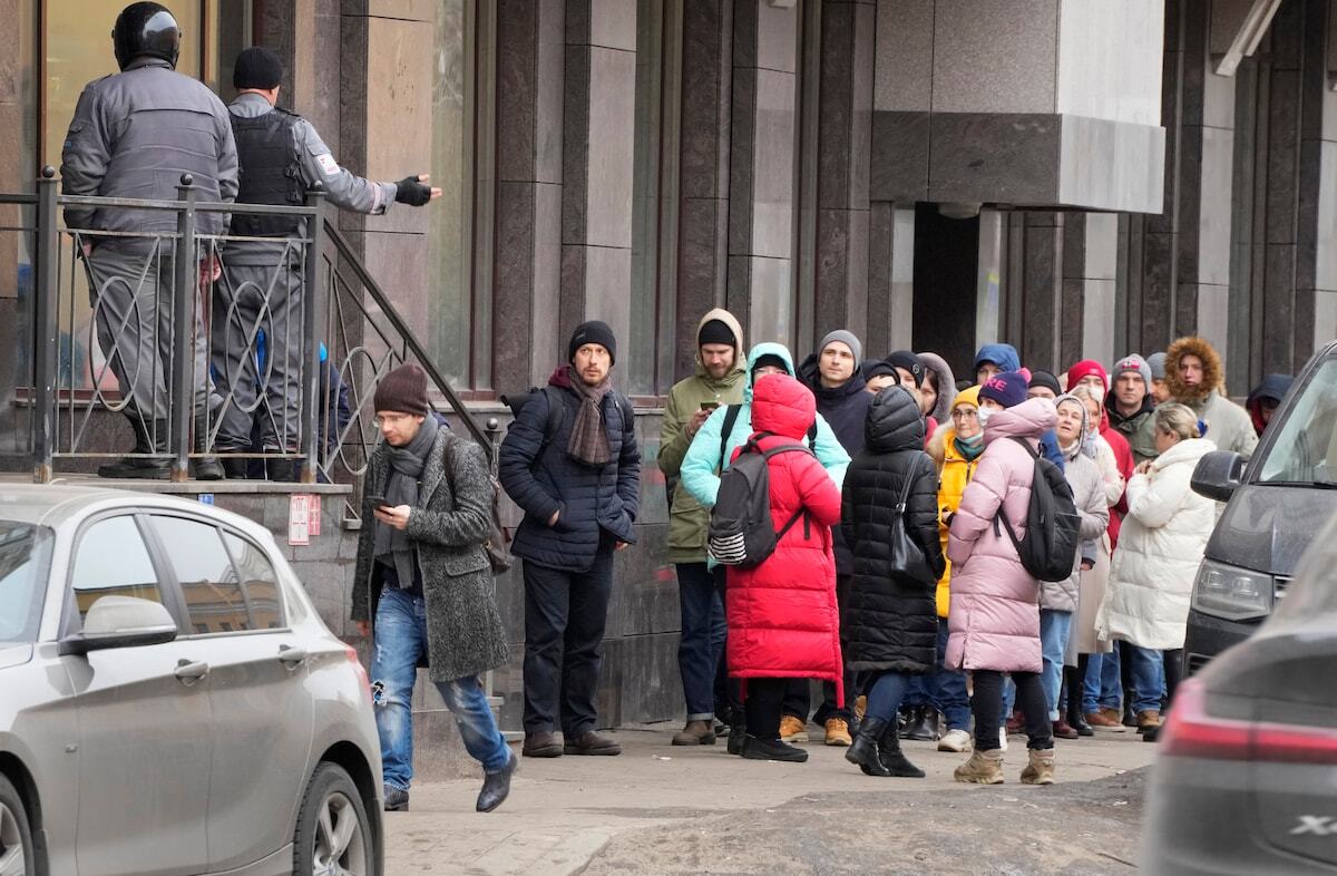 Mọi người xếp hàng để rút đô la Mỹ và euro từ một máy ATM ở St. Petersburg vào ngày 25/2. Ảnh: @Dmitri Lovetsky/AP.