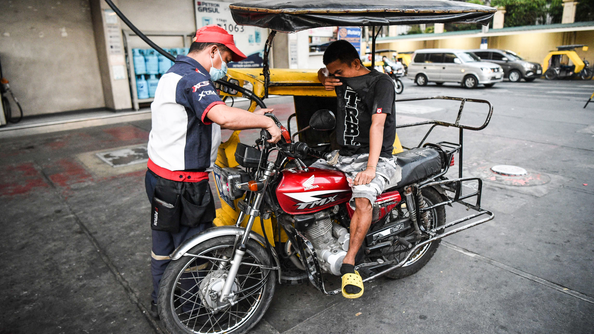 Một người phục vụ đổ xăng cho xe ba bánh tại một trạm xăng ở Manila vào ngày 8 tháng 3. Ảnh: @AFP / Jiji.