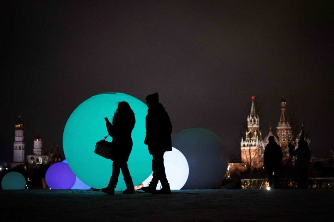 Mọi người đi ngang qua những đồ trang trí Giáng sinh và năm mới có hình những quả cầu tuyết tại công viên Zaryadye ở trung tâm Mátxcơva, gần Điện Kremlin ở Mátxcơva.(Ảnh: @NATALIA KOLESNIKOVA/AFP/ Getty Images).