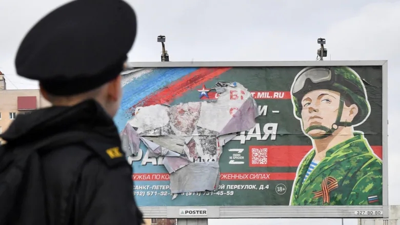 Một học viên quân đội Nga đứng trước một bảng quảng cáo quảng cáo nghĩa vụ quân sự theo hợp đồng ở St. Petersburg vào đầu tháng 10. Nga đã và đang chịu tác động của các biện pháp trừng phạt của phương Tây nhằm bóp nghẹt nền kinh tế của nước này, nhưng cuộc chiến ở Ukraine vẫn tiếp diễn. (Hình ảnh: @Olga Maltseva/AFP/Getty).