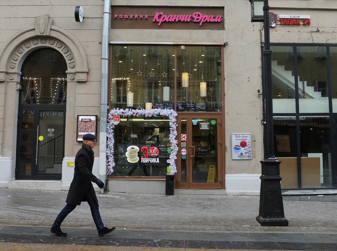 Một người đàn ông đi ngang qua cửa hàng cà phê Krunchy Dream ở Moscow vào tháng trước. Nó được mở tại địa điểm của một cửa hàng Krispy Kreme trước đây, sau khi chuỗi cửa hàng của Hoa Kỳ rời khỏi thị trường Nga. Ảnh: @Evgenia Novozhenina/Reuters.