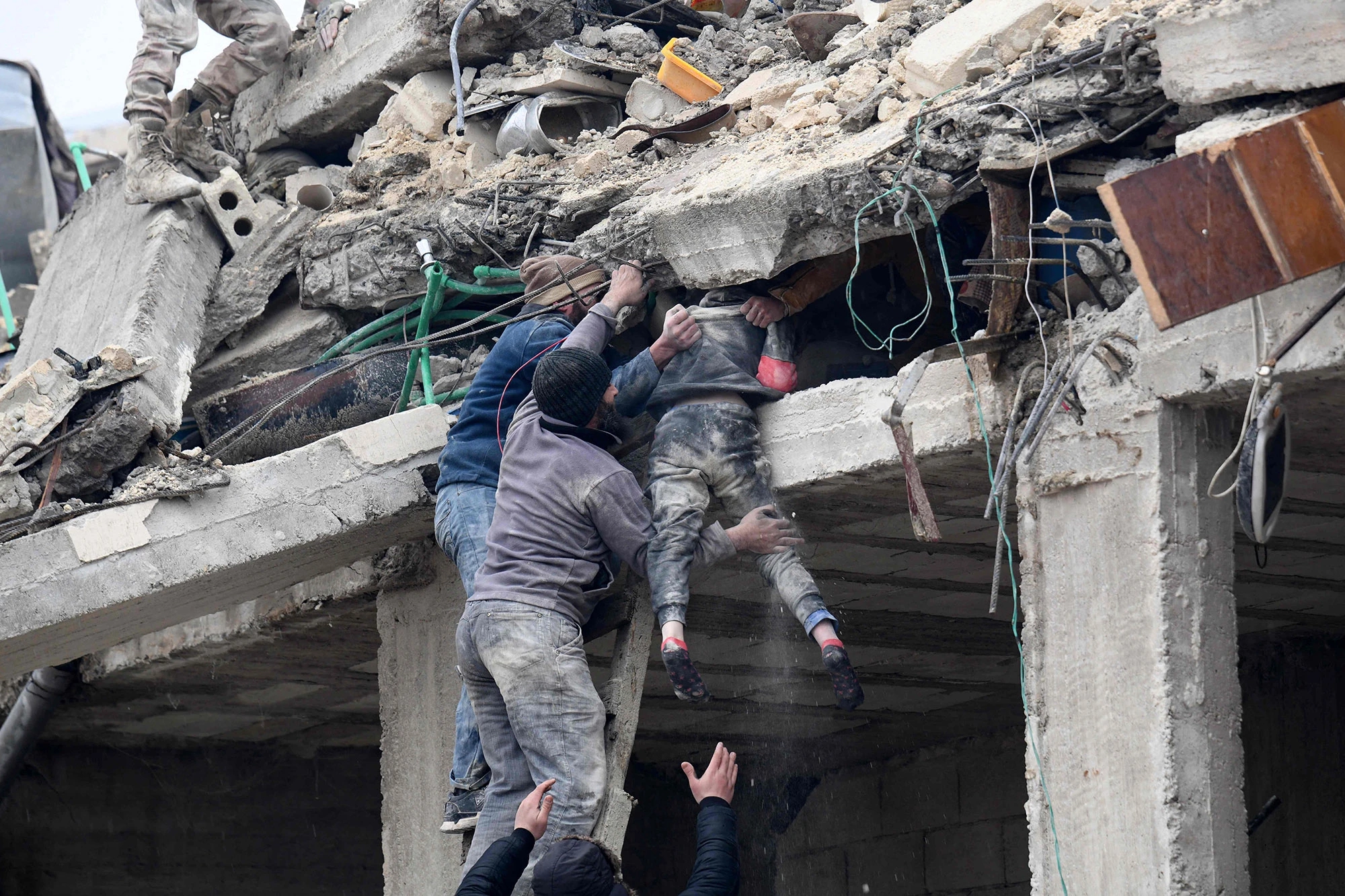 Người dân đưa một bé gái bị thương ra khỏi đống đổ nát của một tòa nhà bị sập sau trận động đất ở thị trấn Jandaris, ở vùng nông thôn của thành phố Afrin phía tây bắc Syria, thuộc khu vực do phiến quân kiểm soát của tỉnh Aleppo, vào ngày 6 tháng 2 năm 2023. Ảnh: @AFP.