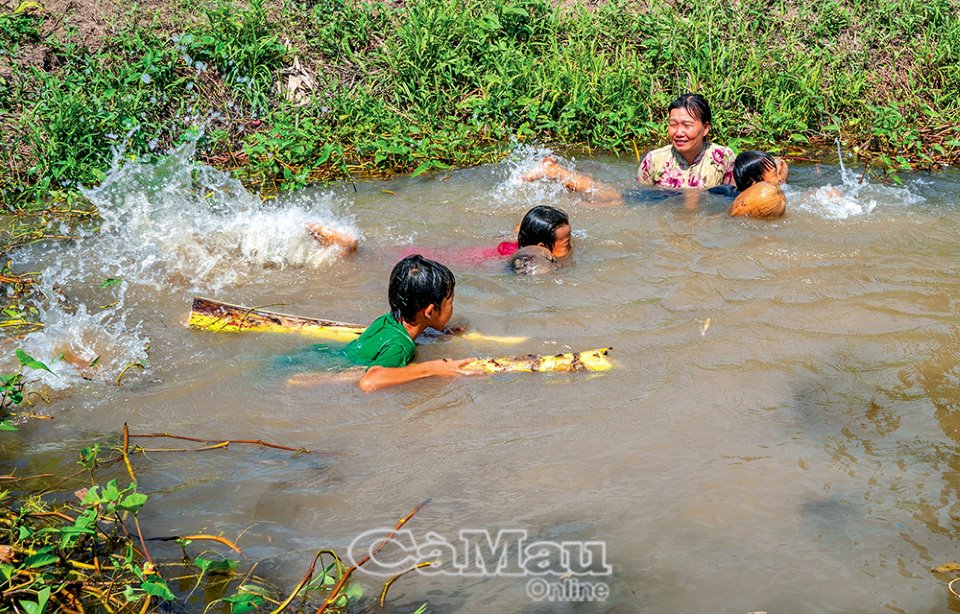 Các chị nông dân ở Cà Mau tung vô số quả dừa khô xuống kênh dạy trẻ em tập bơi, nhiều người đến xem - Ảnh 2.