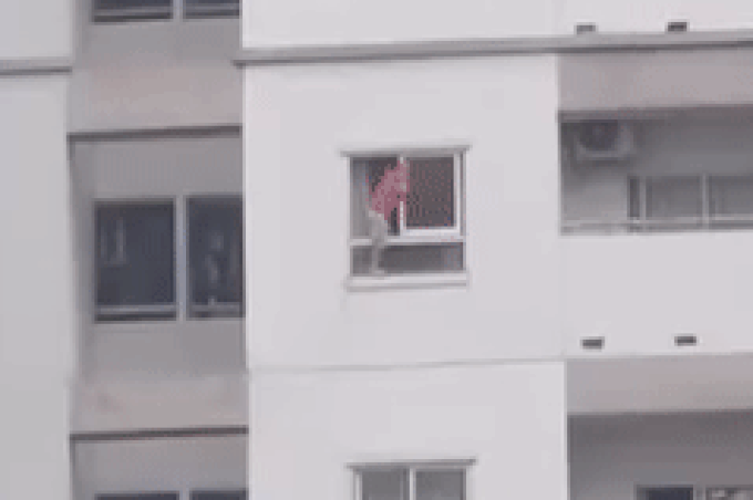 Hãi hùng cảnh bé trai vắt vẻo trên thành cửa sổ tầng cao chung cư - Ảnh 1.