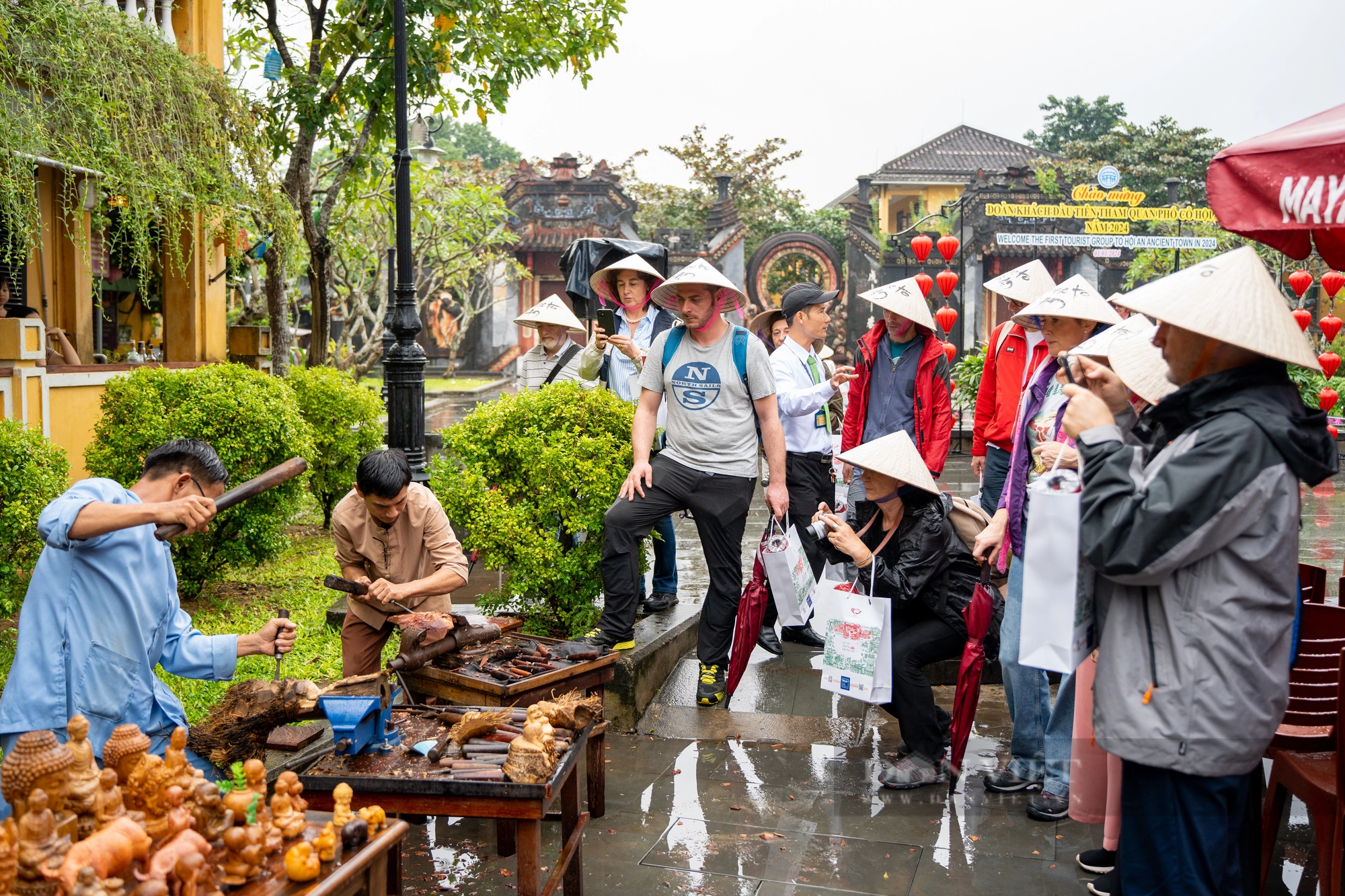 Bất chấp mưa lớn, du khách đội nón lá, thích thú tham quan phố cổ Hội An ngày Tết Dương lịch 2024 - Ảnh 2.