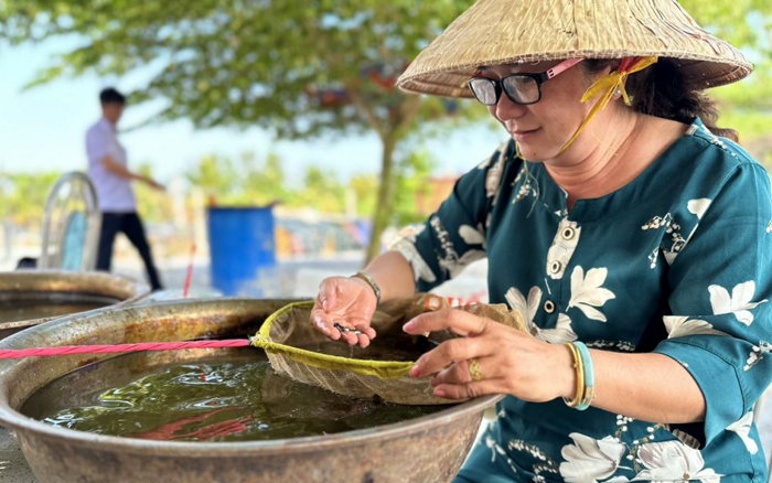 Bà Nguyễn Thị Hồng Nga chăm sóc đàn cá cảnh. Ảnh: Phan Tuyền