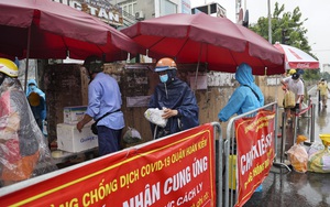 Ảnh: Hàng dài người dân xếp hàng dưới mưa gửi đồ tiếp tế vào khu vực phong tỏa