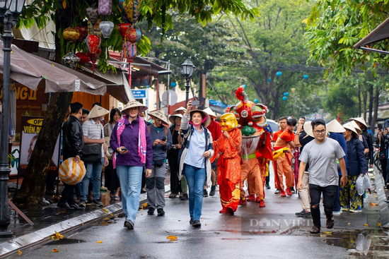 Bất chấp mưa lớn, du khách đội nón lá, thích thú tham quan phố cổ Hội An ngày Tết Dương lịch 2024 - Ảnh 1.