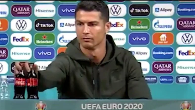 Ronaldo cất 2 chai Coca Cola trên bàn trong buổi họp báo.