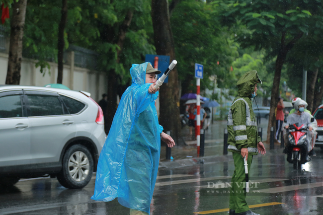 Hình ảnh đẹp chiến sĩ công an dầm mưa hỗ trợ cho sĩ tử - Ảnh 1.