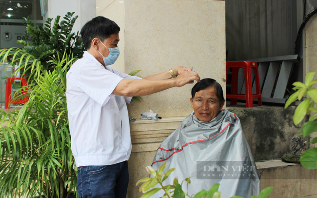 Trên đường Nguyễn Thị Minh Khai (quận 1), 2 nhân viên bảo vệ của Phòng khám Nha khoa thẩm mỹ Đại Nam tranh thủ lúc vắng khách, tự cắt tóc cho nhau.  (Ảnh: Nguyên Vỹ)