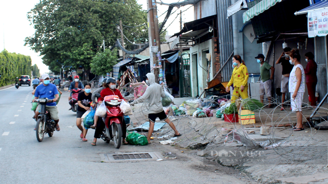 Người dân ranh mua bán rau củ tại các tiệm hàng trên trên đường QL1A, ngay phía trước Chợ đầu mối Thủ Đức. Trước đó, khu vực này đã bị giăng kẽm gai để hạn chế việc mua bán của các tiểu thương. Tất cả phải dịch vừa vội vàng vừa tranh thủ nhìn ngó lực lượng chức năng. (Ảnh: Nguyên Vỹ)