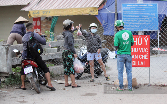 17 giờ 50 tại một chốt kiểm soát ở phường An Phú Đông, quận 12. Người dân tranh thủ giao nhận nhu yếu phẩm cho người thân trong khu cách ly y tế. (Ảnh: Nguyên Vỹ)