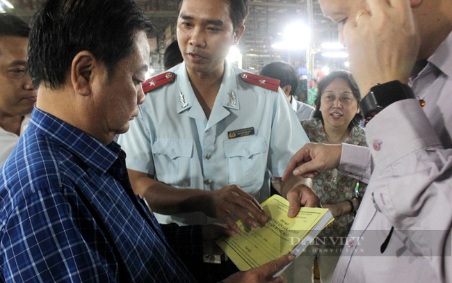 Bộ trưởng Lê Minh Hoan kiểm rea sổ sách ghi chép nhật ký kinh doanh của thương nhân. Ảnh: Nguyên Vỹ