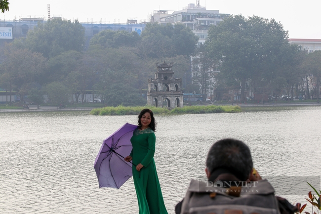 Một thợ ảnh dạo may mắn tìm được khách hàng chụp ảnh lưu niệm bên hồ Hoàn Kiếm.