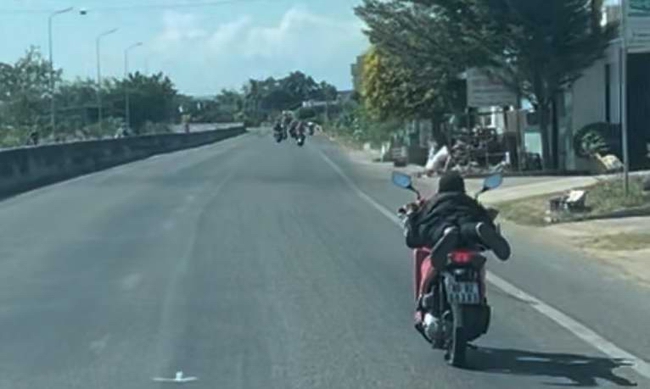 Công an tỉnh Bình Thuận chỉ đạo xử nghiêm thanh niên không đội mũ bảo hiểm nằm trên yên xe máy chạy tốc độ cao - Ảnh 1.