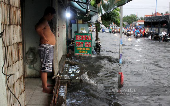 Người dân sống gần điểm ngập ở phường Vĩnh Phú (TP.Thuận An) phải che chắn để nước không tràn vào nhà. Ảnh: Nguyên Vỹ