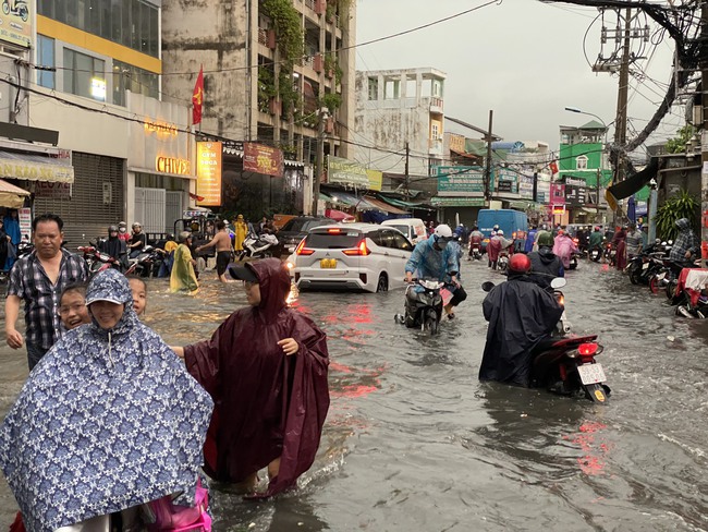 Người dân TP.HCM vật vã dưới trời mưa lớn, nhiều nơi đã ngập - Ảnh 1.