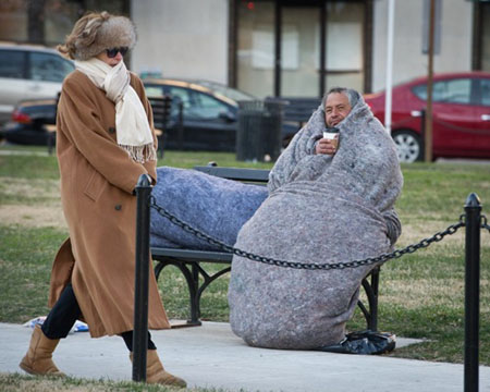 Một phụ nữ bước ngang qua một người vô gia cư ở Quảng trường McPherson khi nhiệt độ hạ xuống dưới 0 độ C tại Washington. Ảnh: AFP 