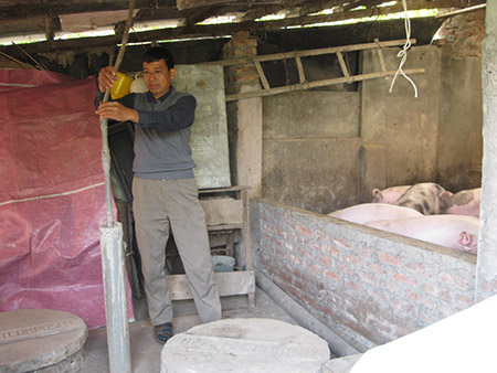 Ông Bùi Văn Thuần đang kiểm tra lại đường ống dẫn khí Bioga của gia đình ở thôn Hạ, xã Hồng Phong (Chương Mỹ, Hà Nội).