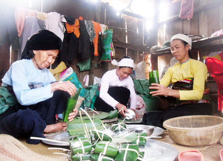 Ba mẹ con quây quần cùng nhau gói những chiếc bánh chưng.