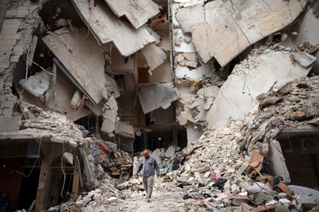 Một người đàn ông Syria tìm kiếm những thứ còn sót lại từ tòa nhà đổ nát do đạn pháo.