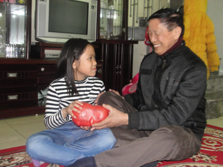 Ông Triệu Đình Khuê tặng lợn nhựa cho học sinh, giúp các em tự giác tiết kiệm bằng việc nuôi lợn nhựa.