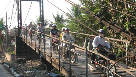 Cây cầu treo thị trấn Thủ Thừa hàng ngày phải “gồng mình” gánh chịu hàng nghìn lượt người qua lại trên cầu.