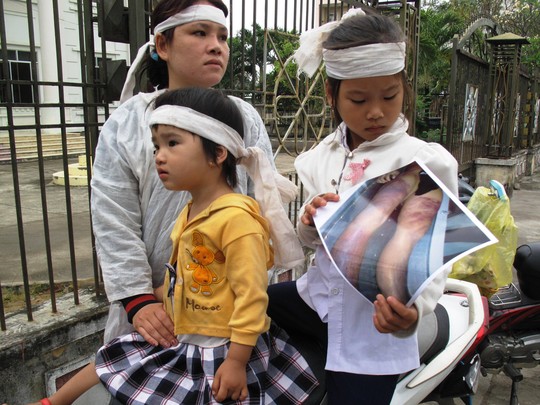 Chị Trần Thị Tâm (vợ Kiều) cùng 2 con mang theo ảnh cồng ra tòa