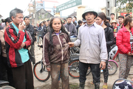 Bà Lê Thị Thoa mặc nguyên bộ quần áo bê bết bùn do bị công an xô  ngã dúi dụi xuống ruộng lên hội trường thôn phản đối.