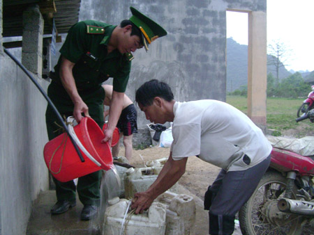 Trung úy Trần Văn Phát múc nước từ bể chứa của công trình nước sinh hoạt  cho người dân xóm Giảng Gà.