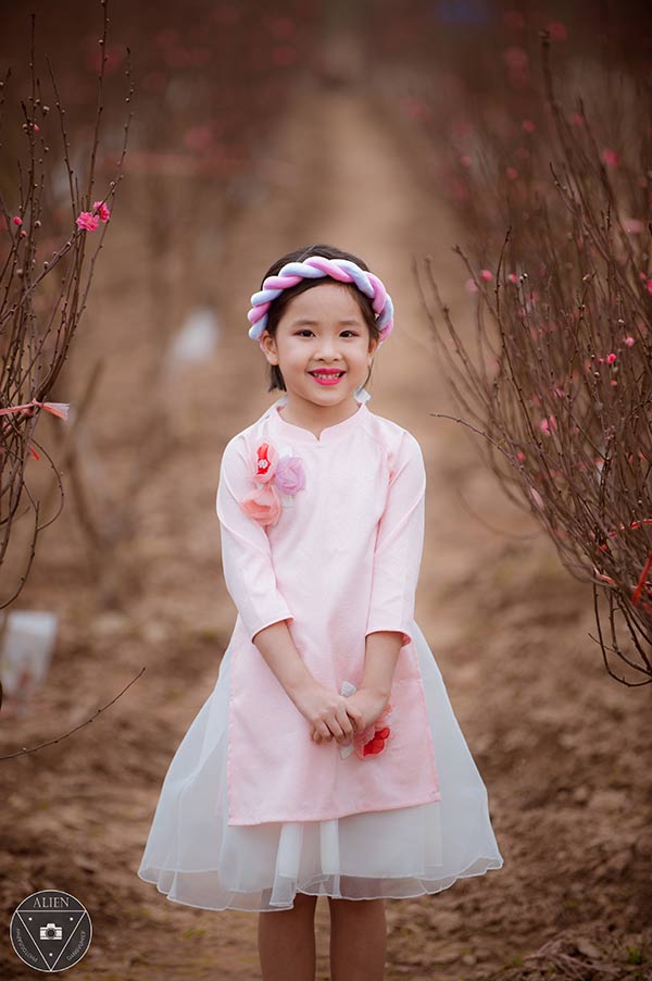 Xem ảnh áo dài và vườn đào đầy màu sắc này để tận hưởng vẻ đẹp truyền thống của Việt Nam thông qua mẫu áo dài sang trọng và những cành đào đỏ yêu kiều của vườn hoa.